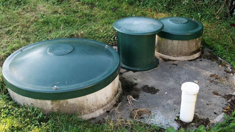 A Septic Tank With Three Green Lids And A White Pipe In The Grass — All Hours Vac Truck In Yeppoon, QLD