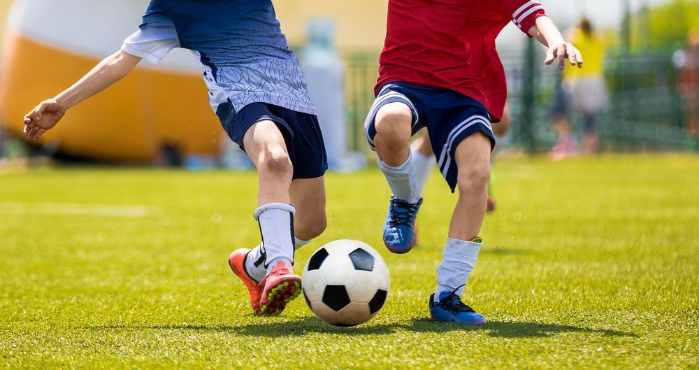 Two Young Boys Are Playing Soccer On A Field — All Hours Vac Truck In Rockhampton, QLD