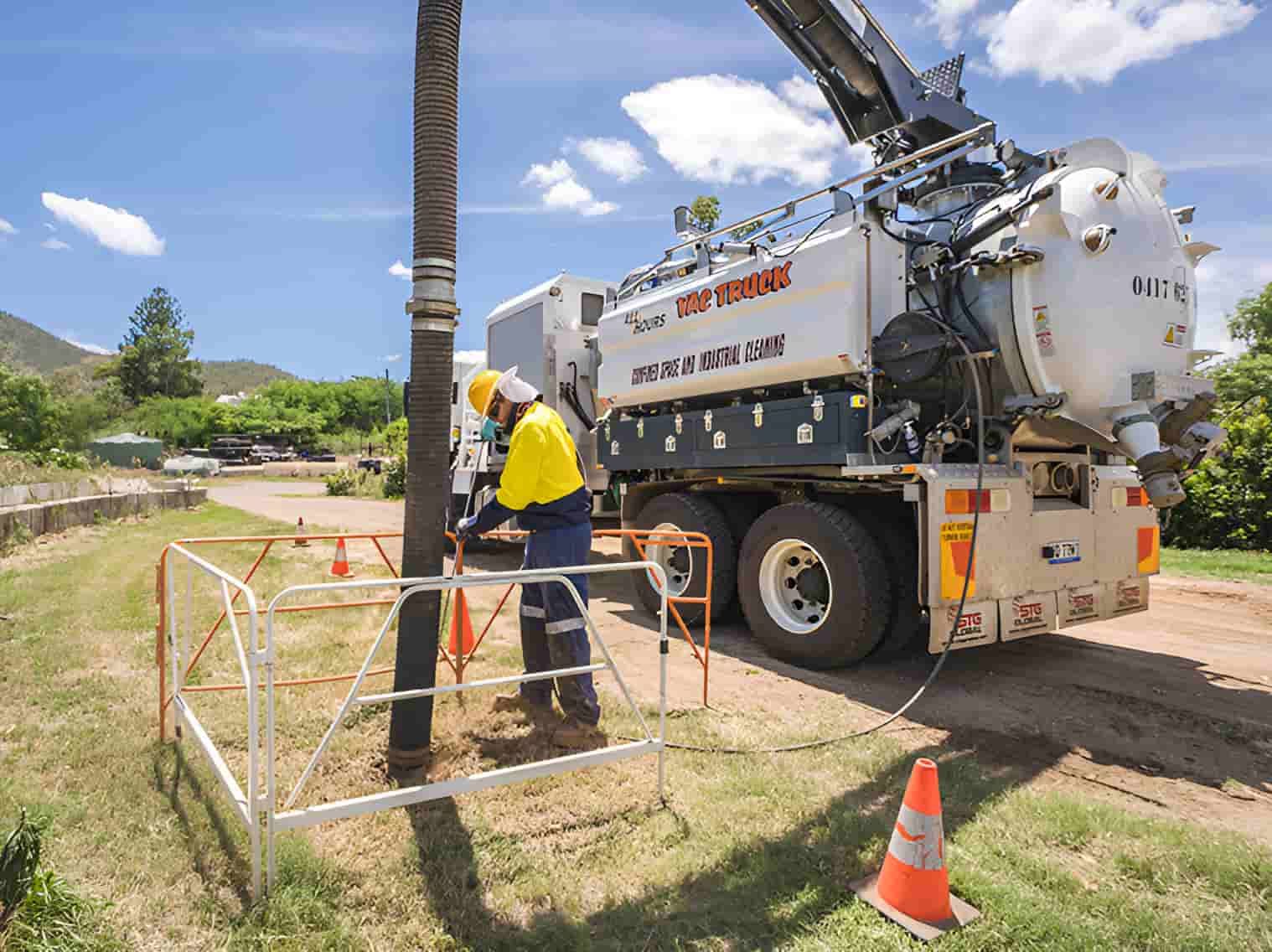 A Man Is Standing Next To A Vacuum Truck On A Dirt Road — All Hours Vac Truck In Lakes Creek, QLD