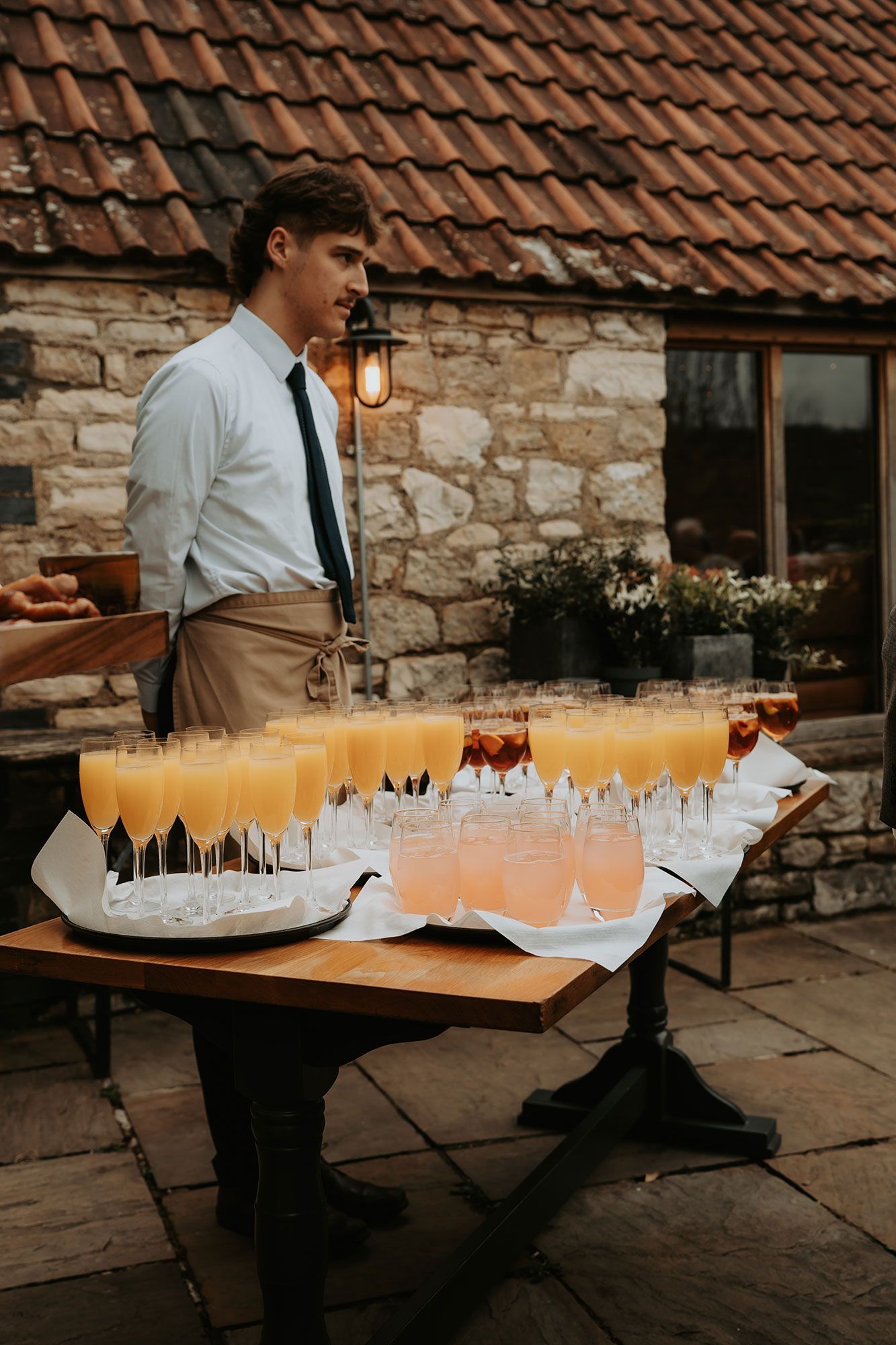 two women are carrying trays of champagne glasses .