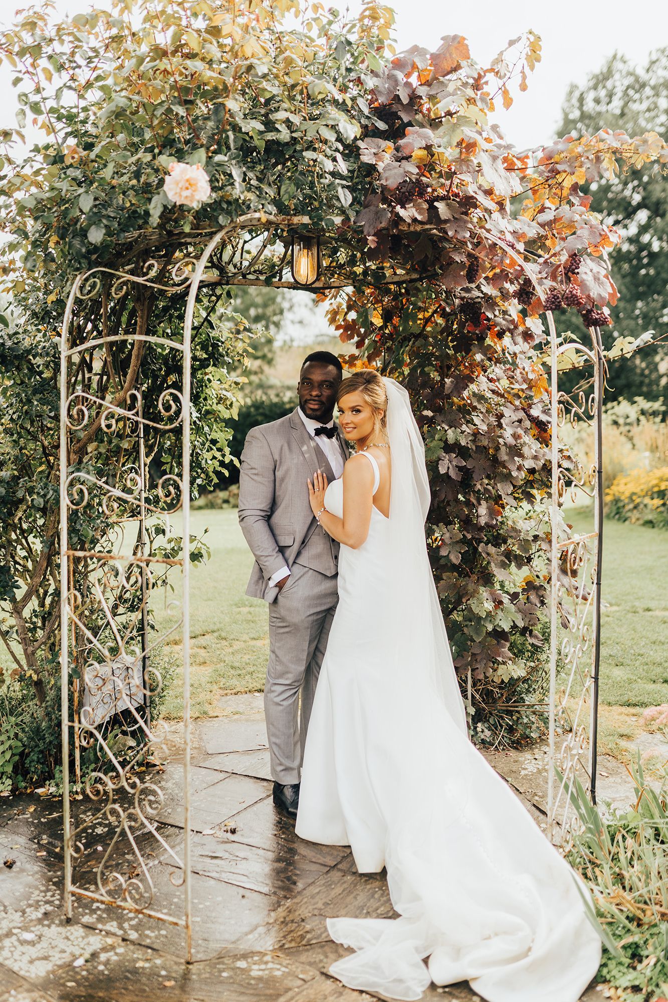 A bride and groom are posing for a picture under an archway.