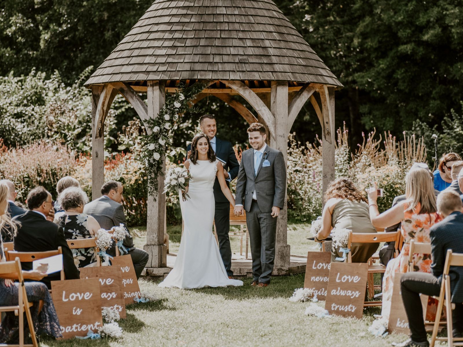 A bride and groom are holding hands during their wedding ceremony under a gazebo.