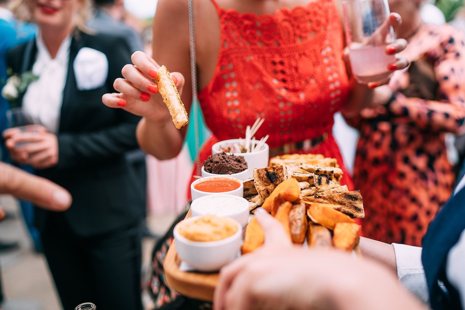 A woman in a red dress is holding a tray of food.