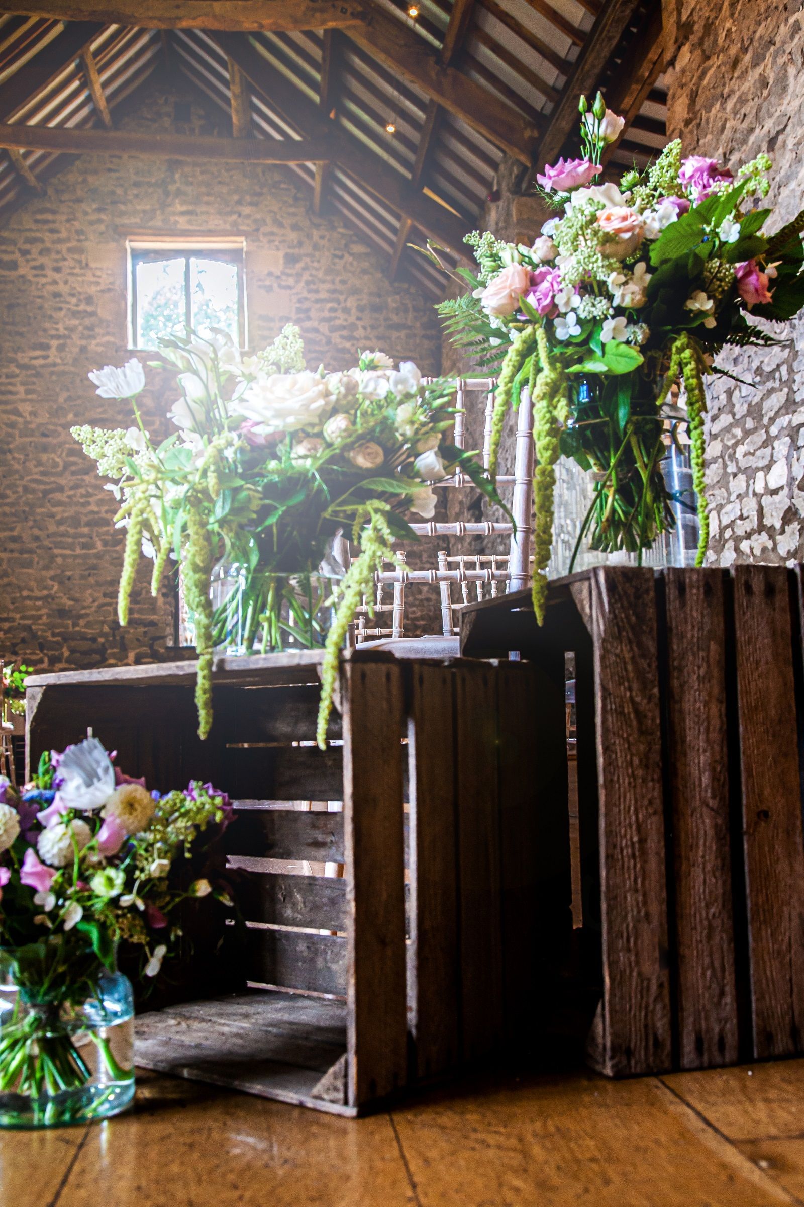 A bunch of vases filled with flowers are sitting on wooden crates in a room.