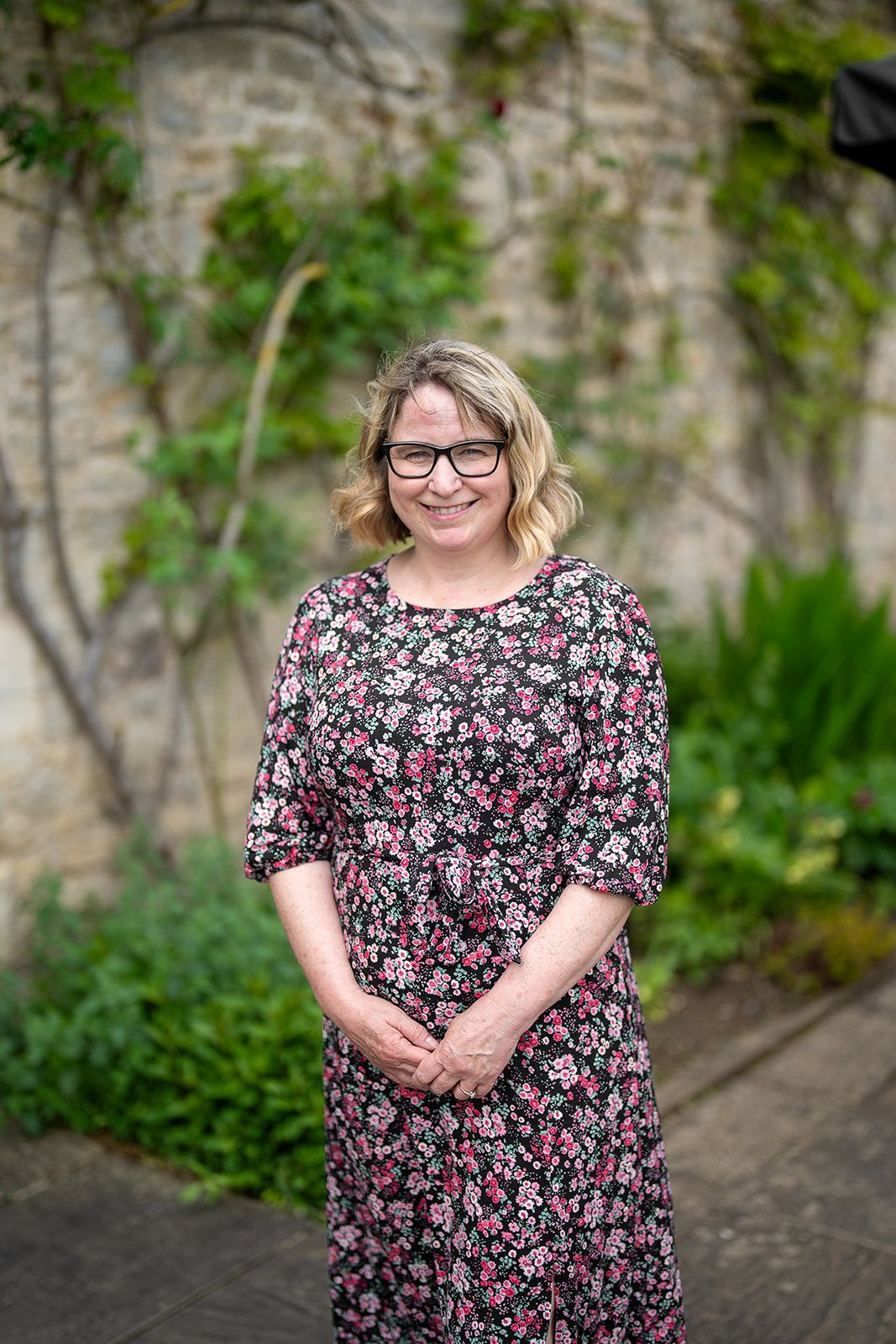 A lady stood in front of a climbing rose