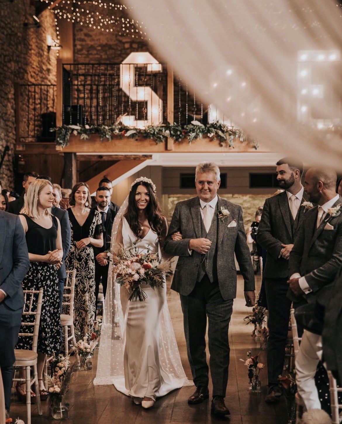 A bride and her father are walking down the aisle at a wedding.