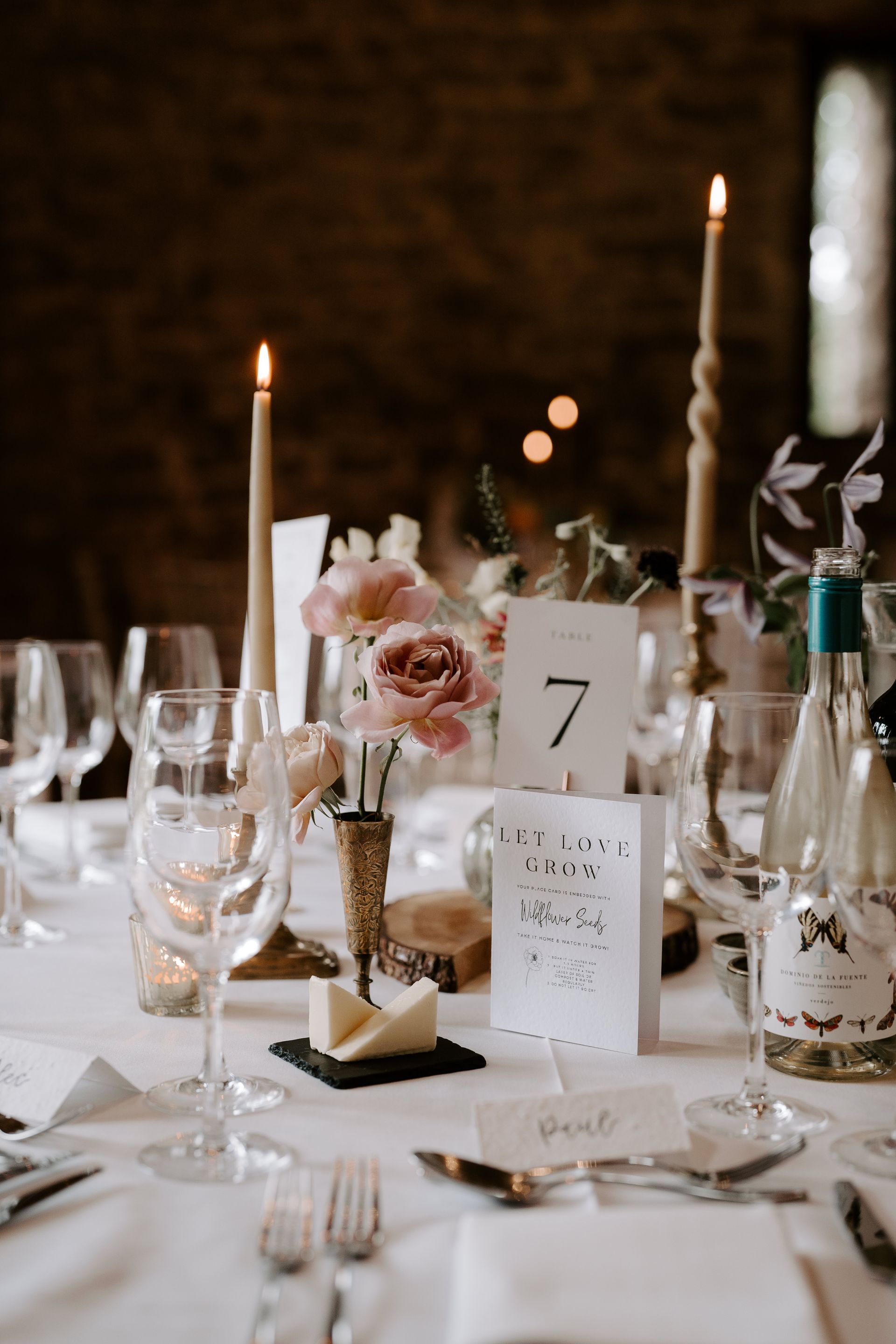 A table set for a wedding reception with candles and flowers on it.
