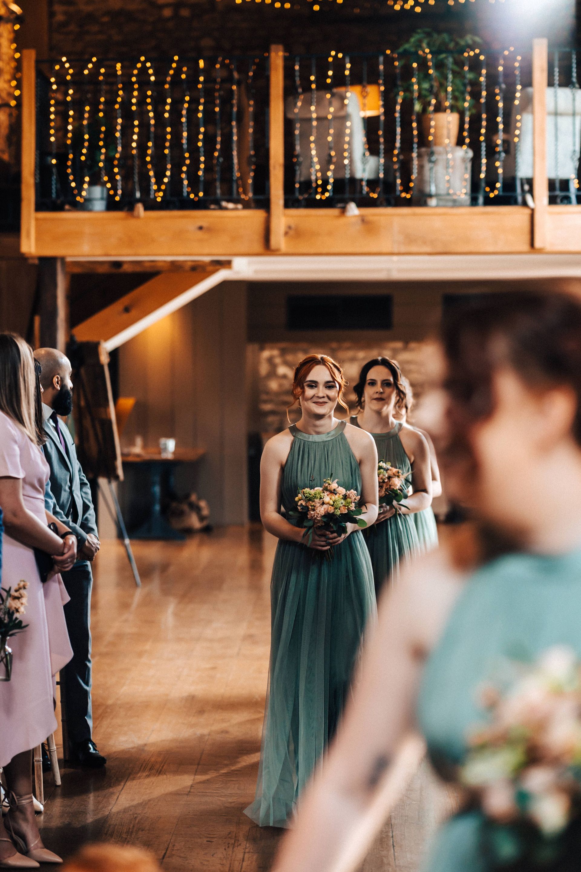 A bride and her bridesmaids are walking down the aisle at a wedding.
