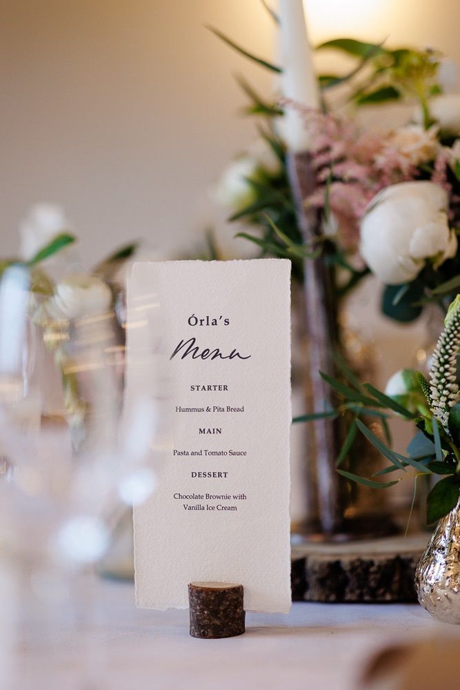 A menu is sitting on a table next to a vase of flowers.