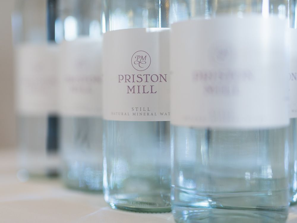Bottles of priston mill water are lined up on a table