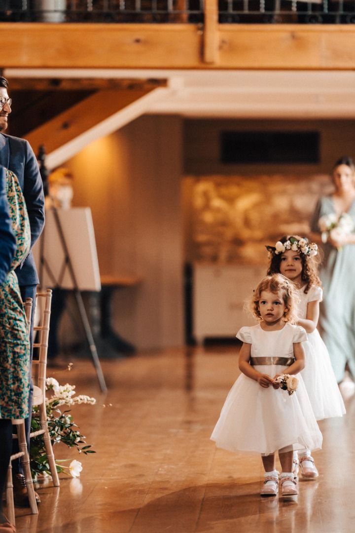 A group of flower girls are walking down the aisle at a wedding.