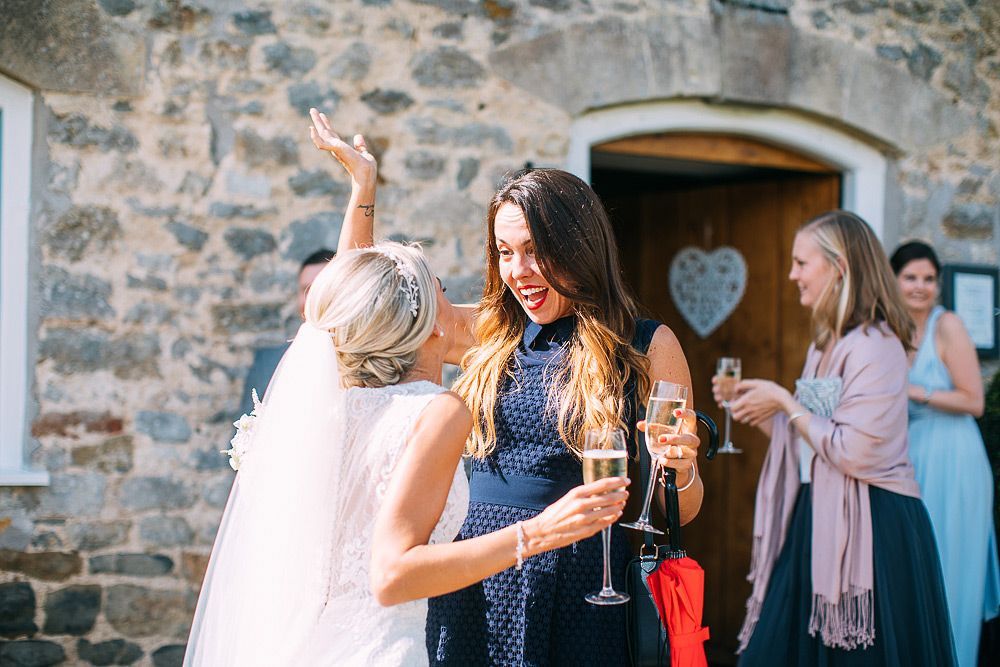 A group of women are standing in front of a stone building holding champagne glasses.