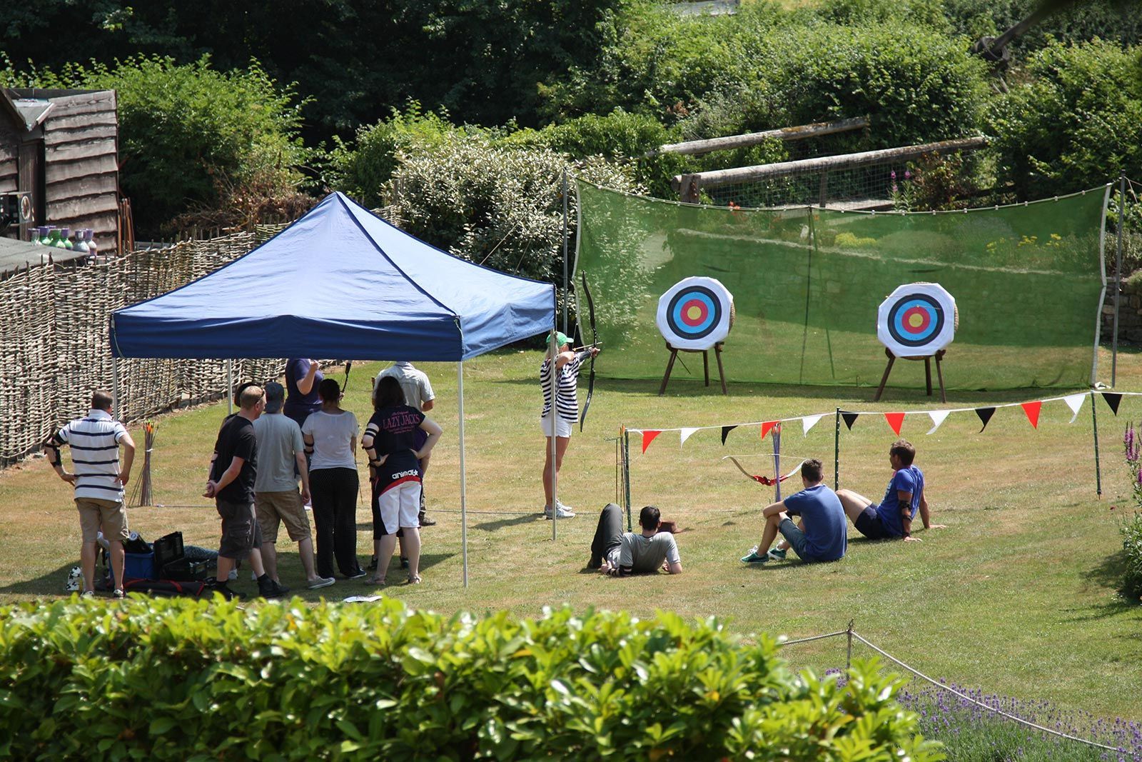 A group of people are standing around a field with archery targets.