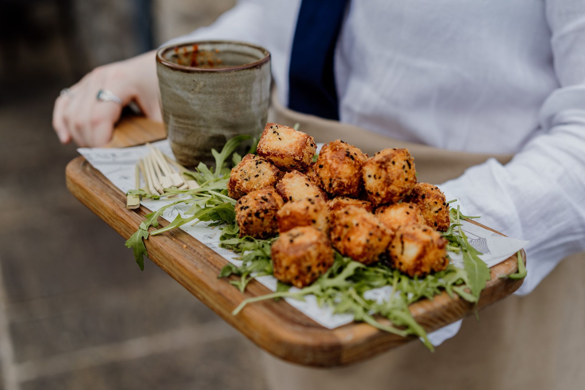 A person is holding a tray of food and a cup of coffee.