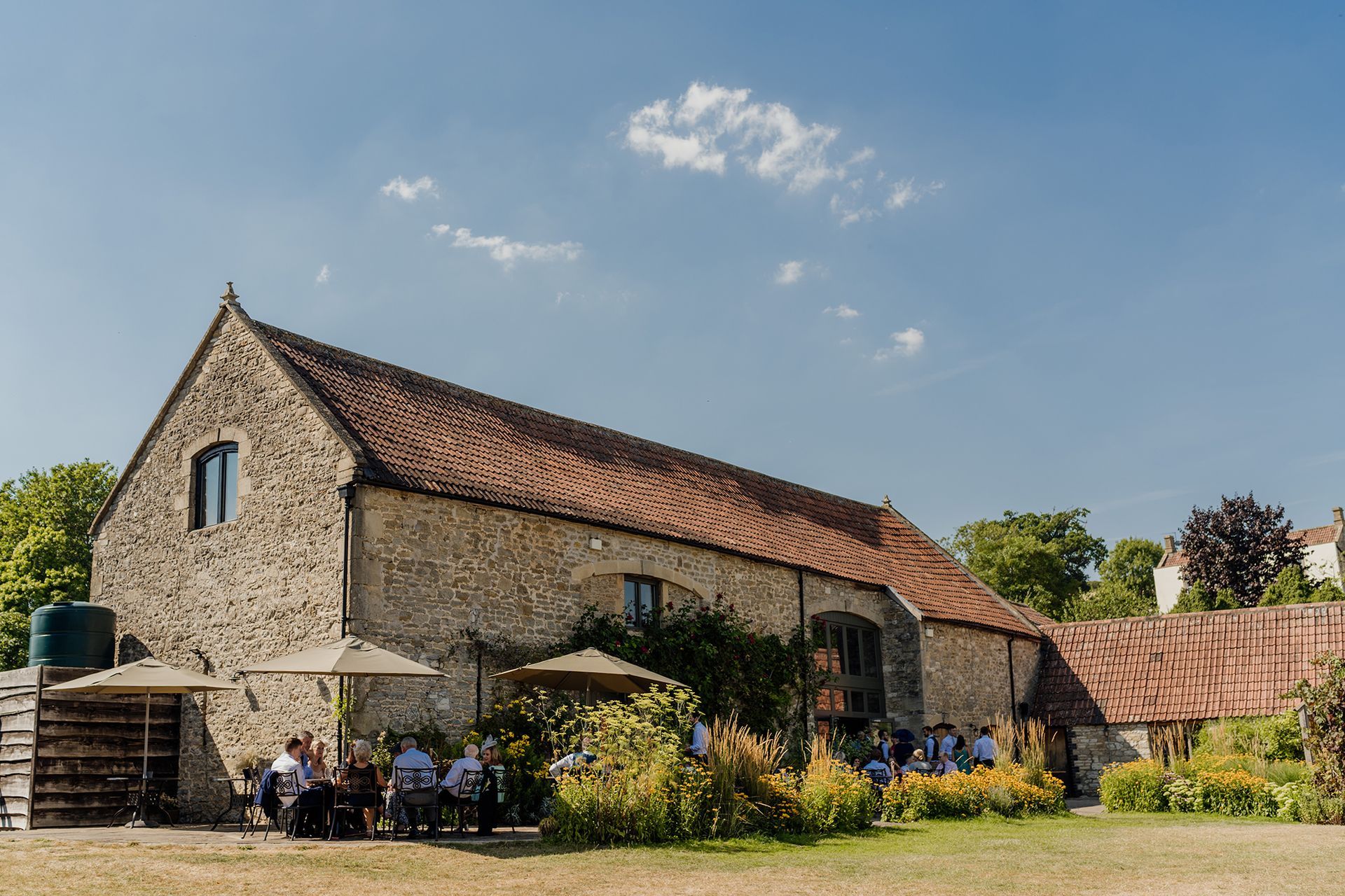 A group of people are sitting under umbrellas in front of a large stone building.
