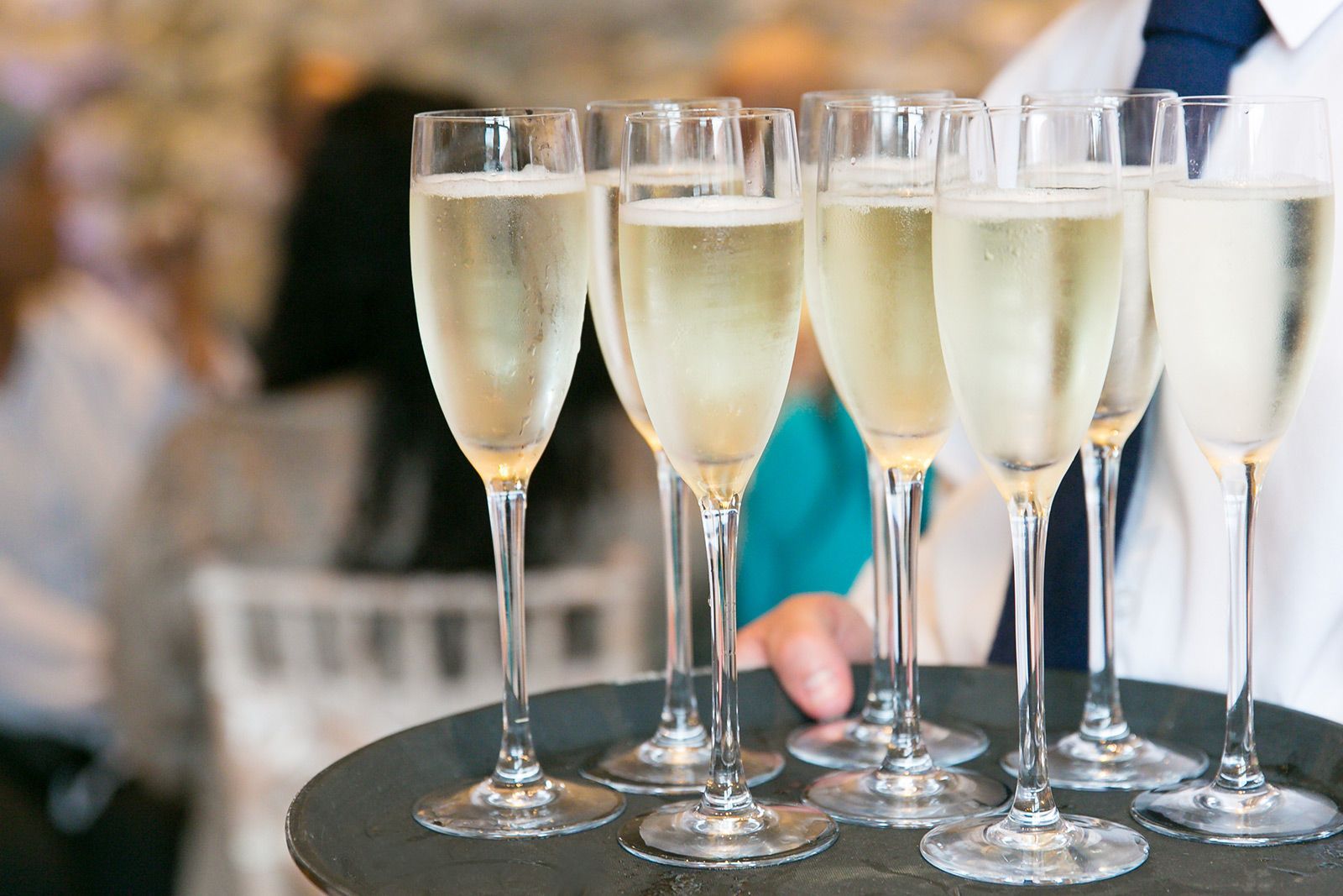 a woman is holding a tray of champagne glasses .