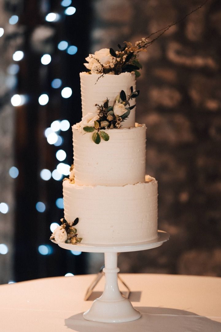 A white wedding cake is sitting on top of a white table.