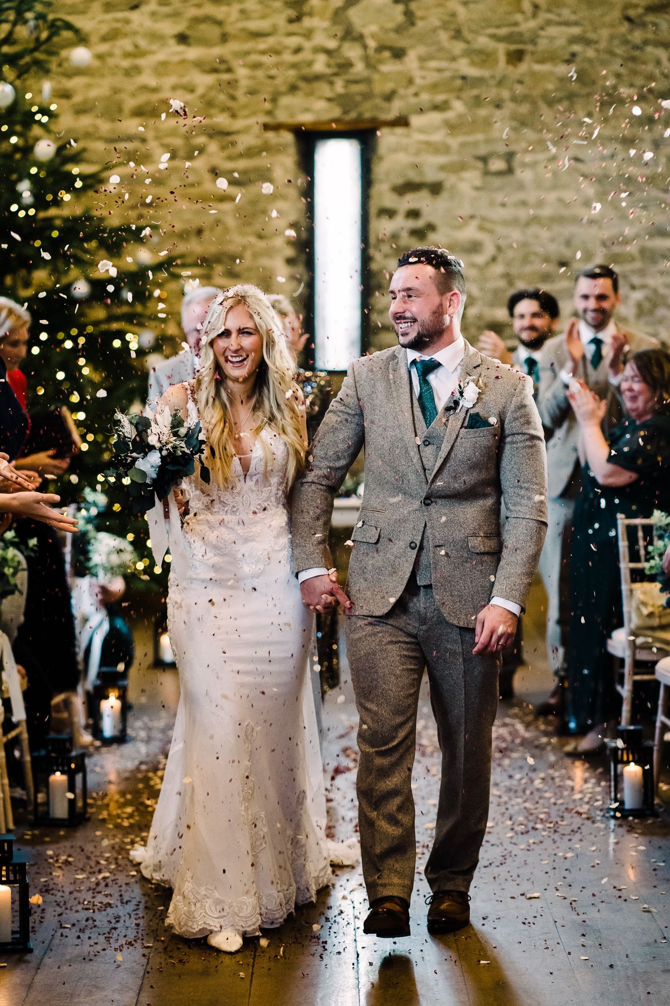 A bride and groom are walking down the aisle holding hands.
