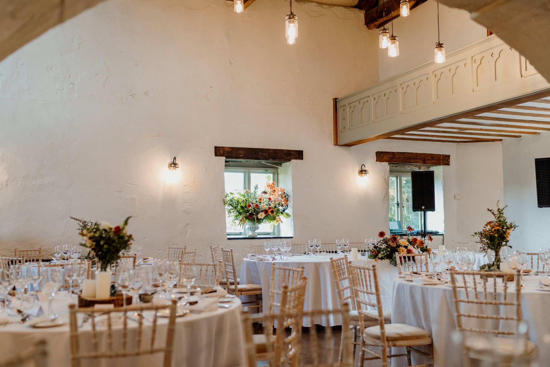 A large room with tables and chairs set up for a wedding reception.
