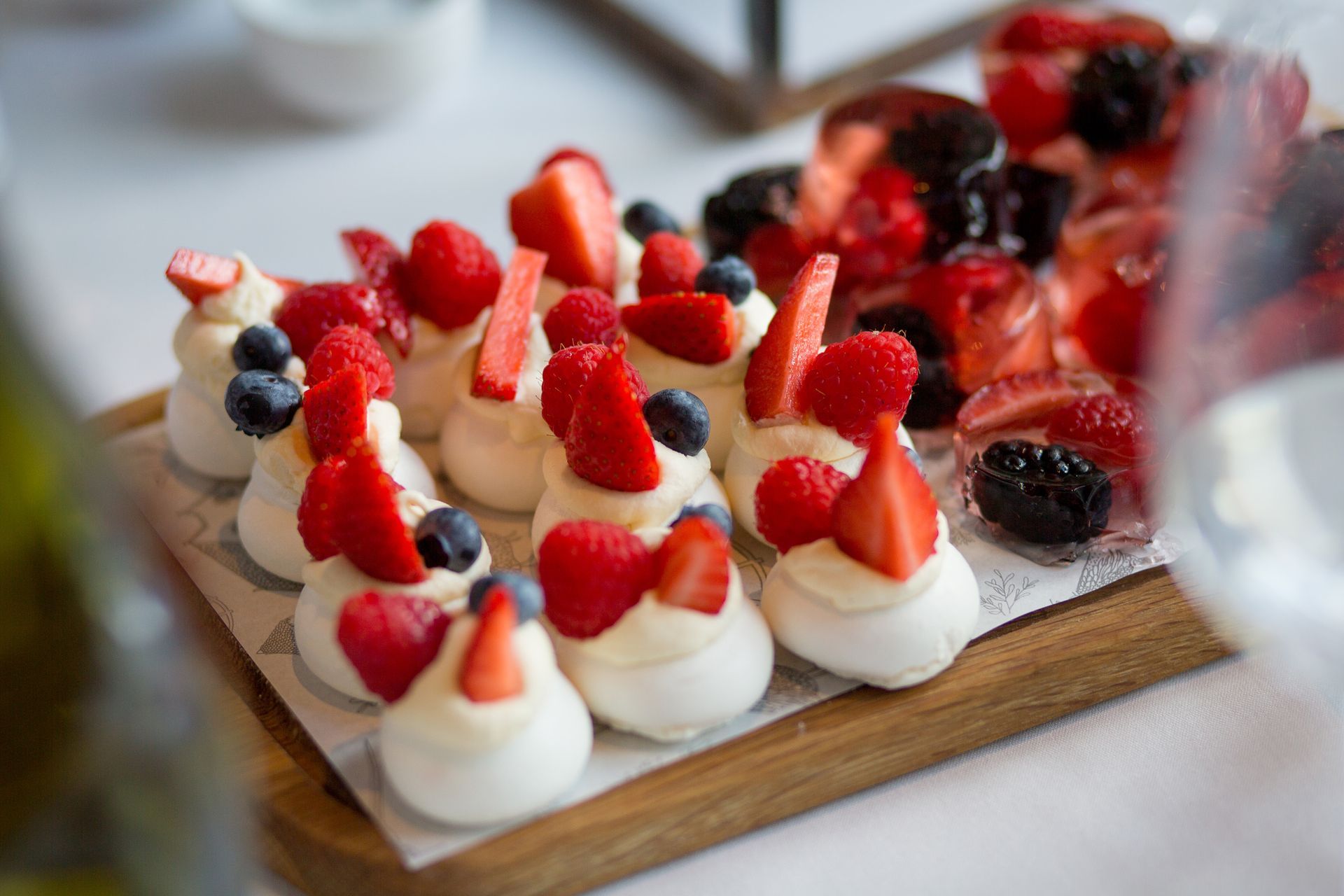 A wooden cutting board topped with meringue and berries.