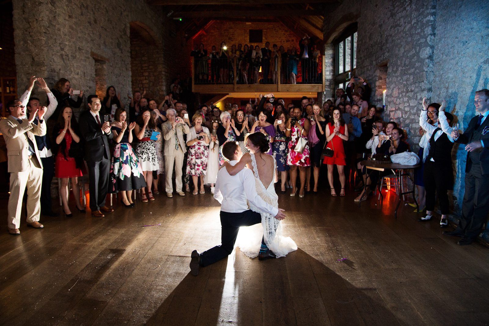 A bride and groom are dancing in front of a crowd of people at a wedding reception.