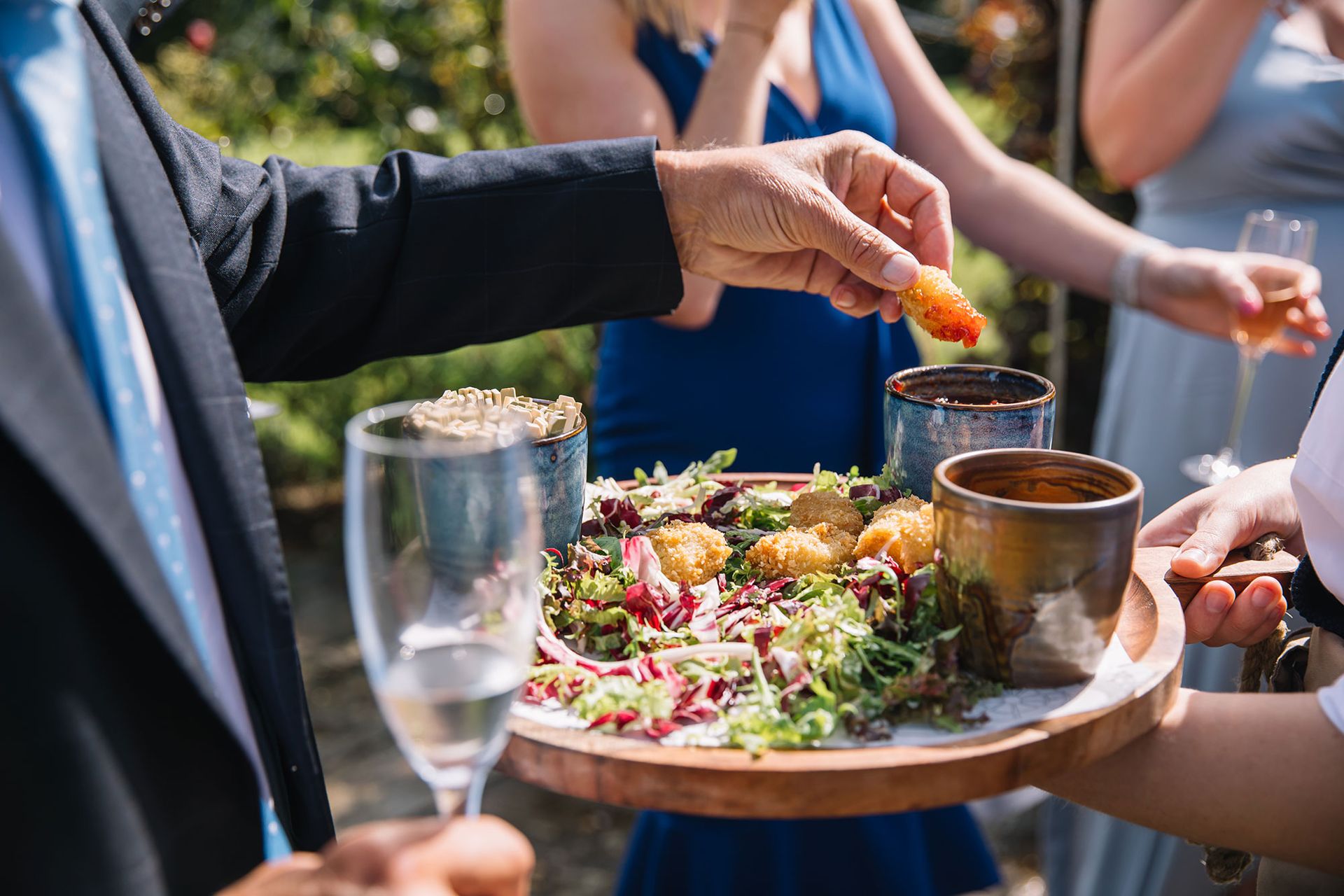 A man is holding a wooden tray with food on it.