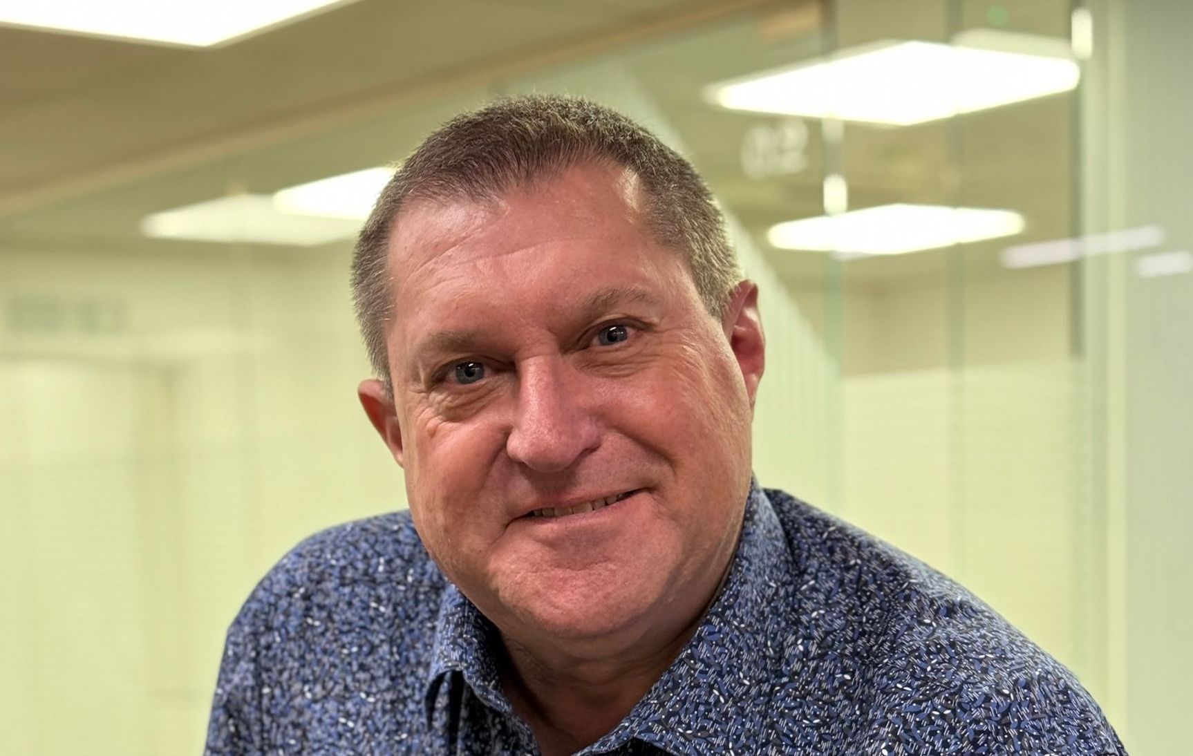 A man in a blue shirt is smiling for the camera.