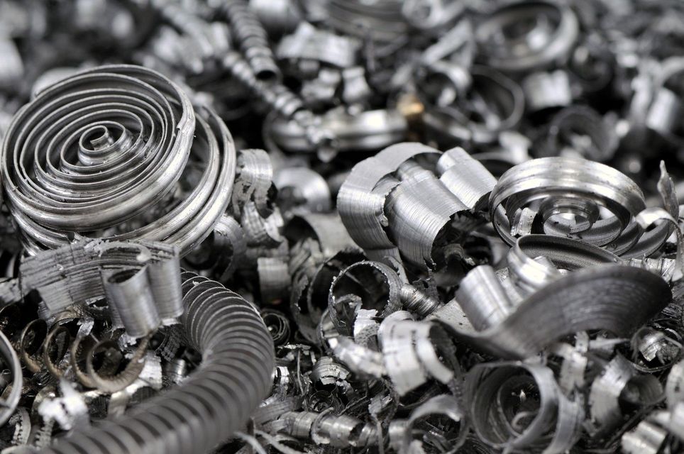 Mucchio di trucioli di metallo argentato, strettamente arricciati e sparsi, provenienti dalla lavorazione meccanica
