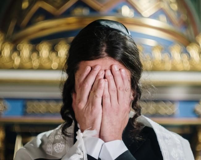 Orthodox Jewish man with face covered, wearing kippah, peyot, and tzitzit