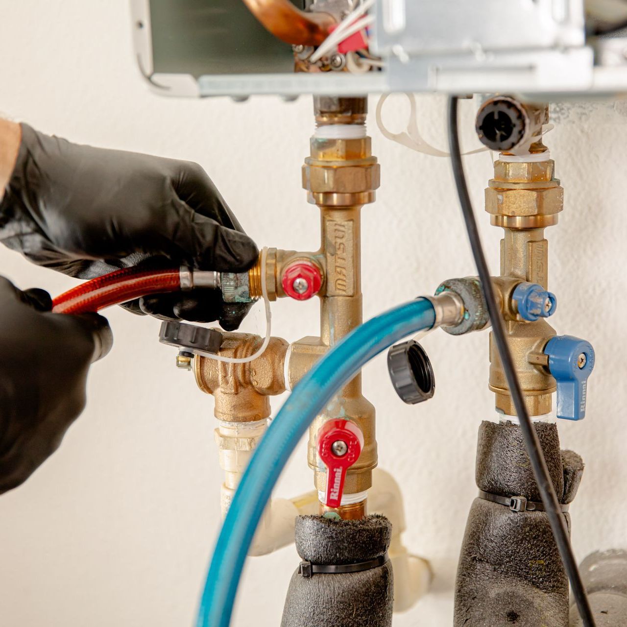 A man is working on a water pump with a water meter in the background.