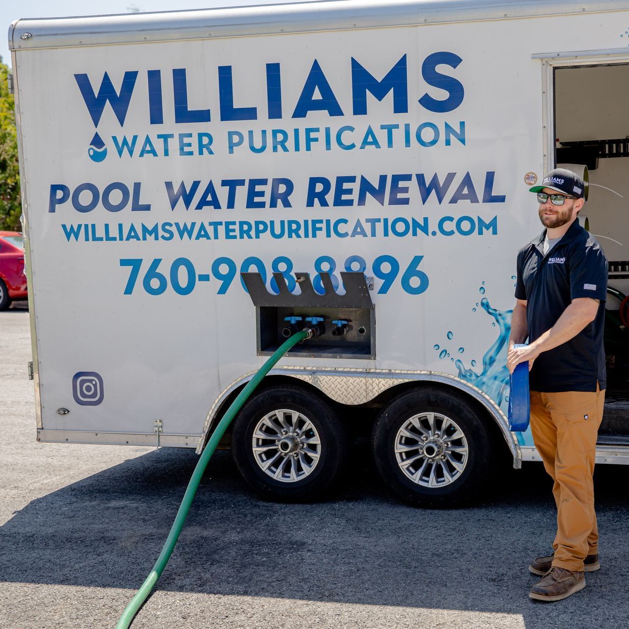 A man is standing in front of a williams water purification truck