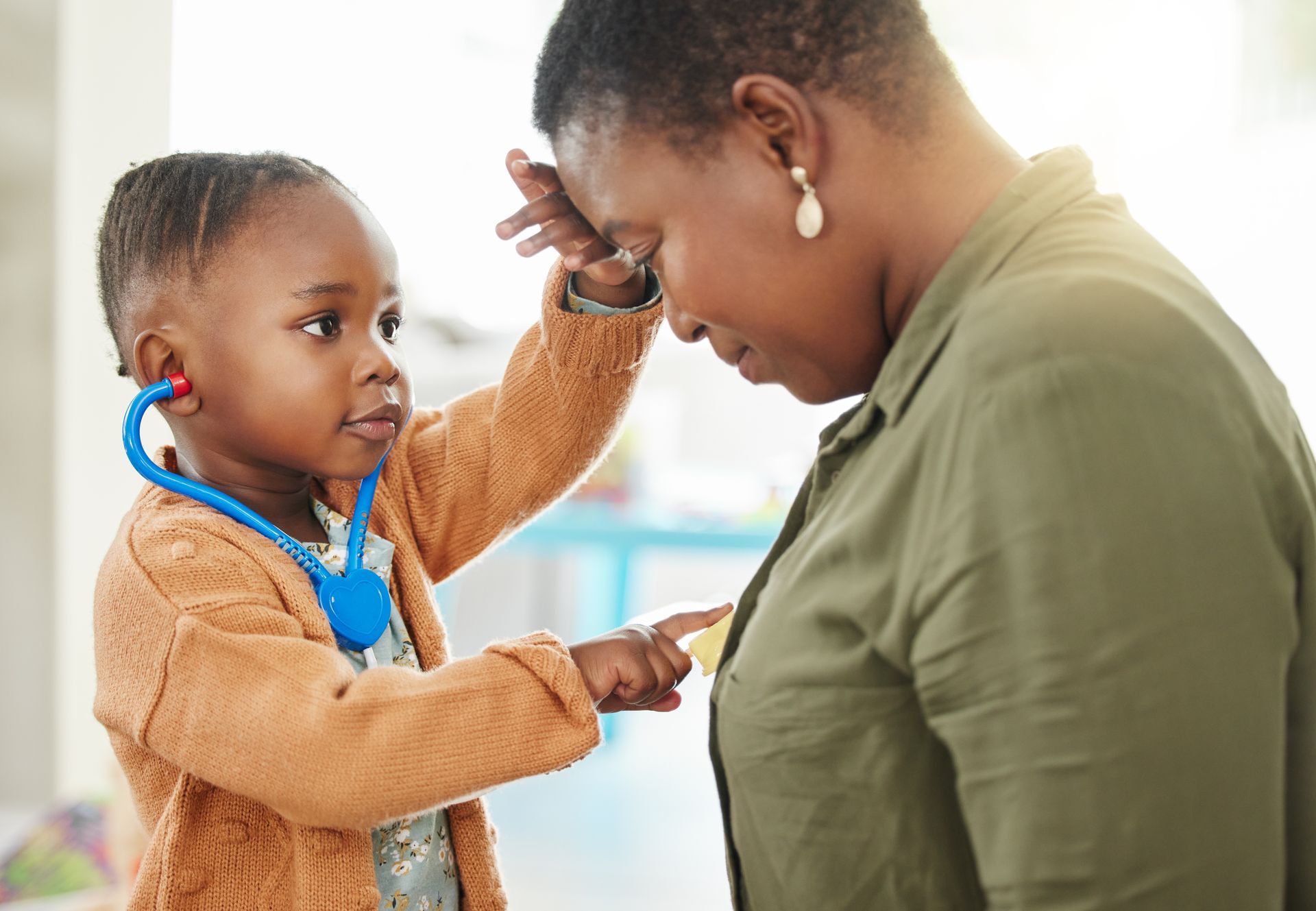 A boy is listening to a women's heart with a play stethoscope