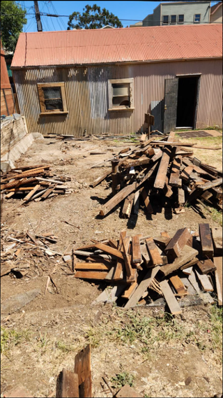 A pile of wood is sitting in front of a building.