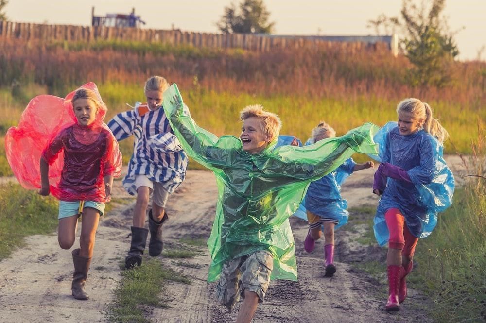 A group of children are running down a dirt road.