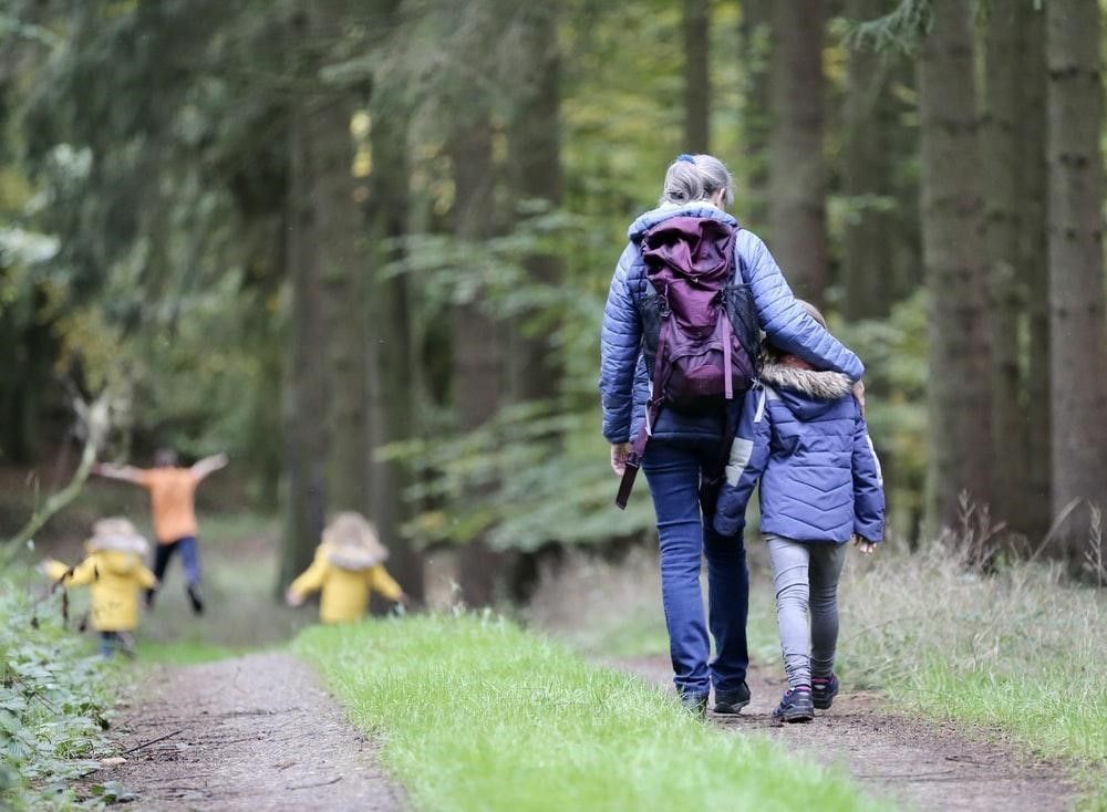 A woman and two children are walking down a path in the woods.