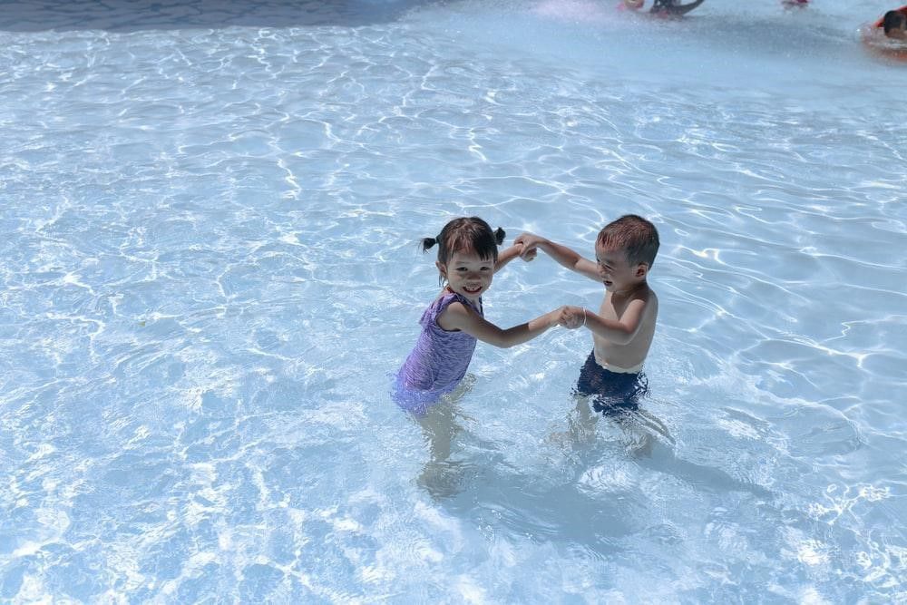 A boy and a girl are playing in a swimming pool.