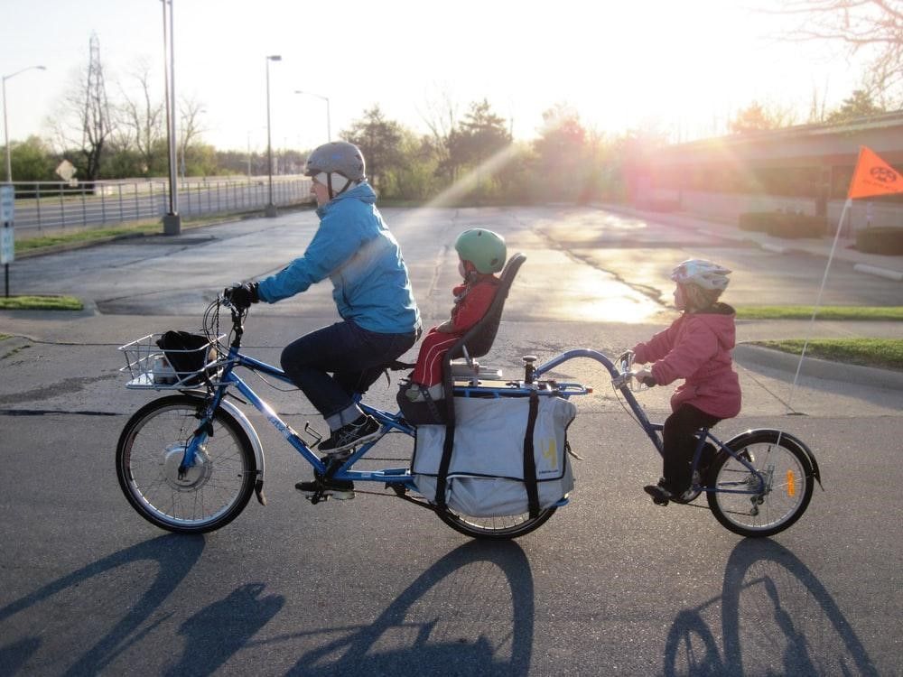 A man and two children are riding a tandem bike