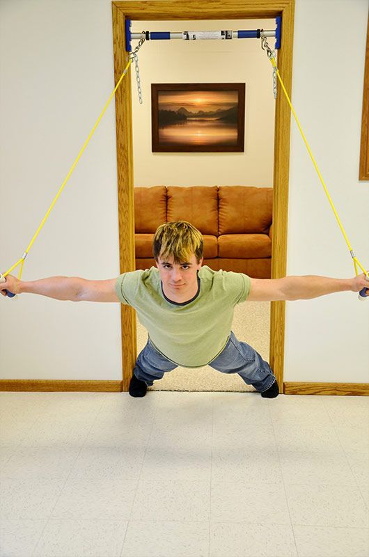 A man is doing push ups in a doorway with a resistance band.