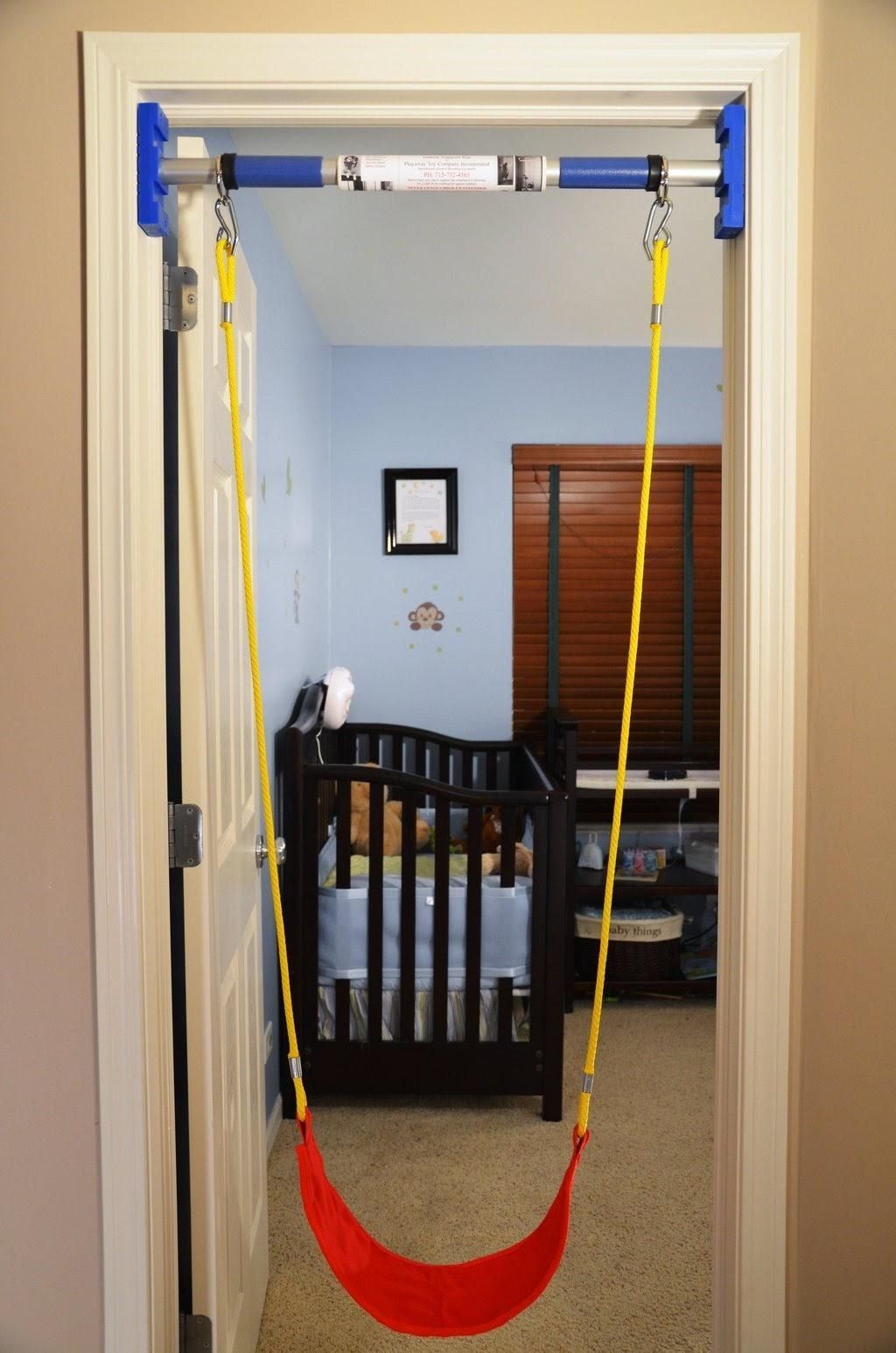 A doorway with a swing attached to it and a crib in the background