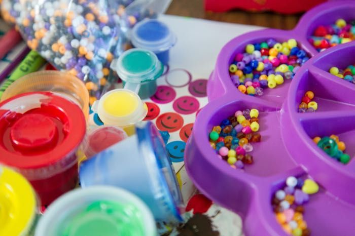 A purple flower shaped tray filled with colorful beads and paint.