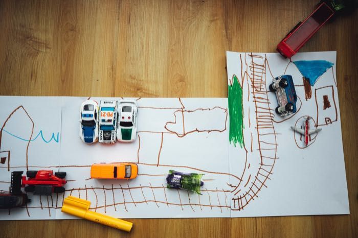 A child 's drawing of a train track with toy cars on it.