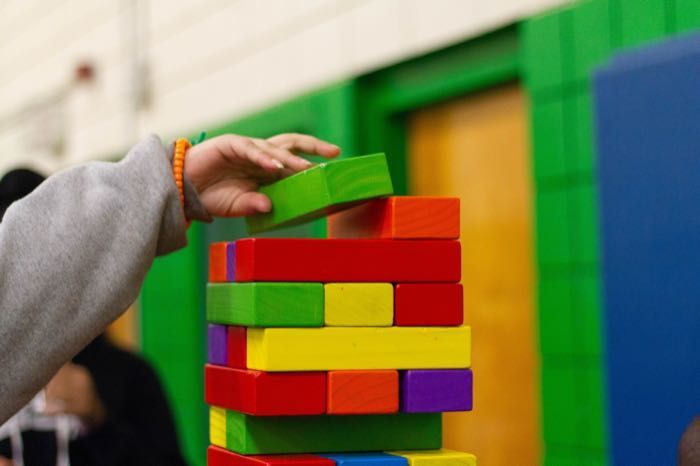 A person is stacking colorful wooden blocks on top of each other.