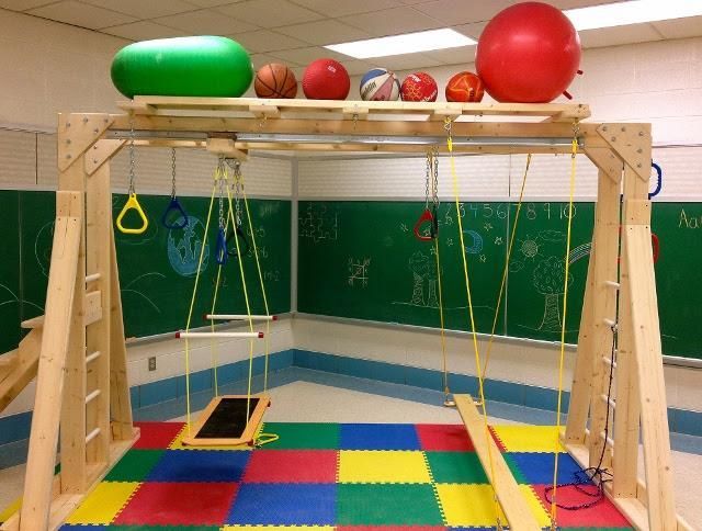 A classroom with a swing and balls on top of a wooden structure