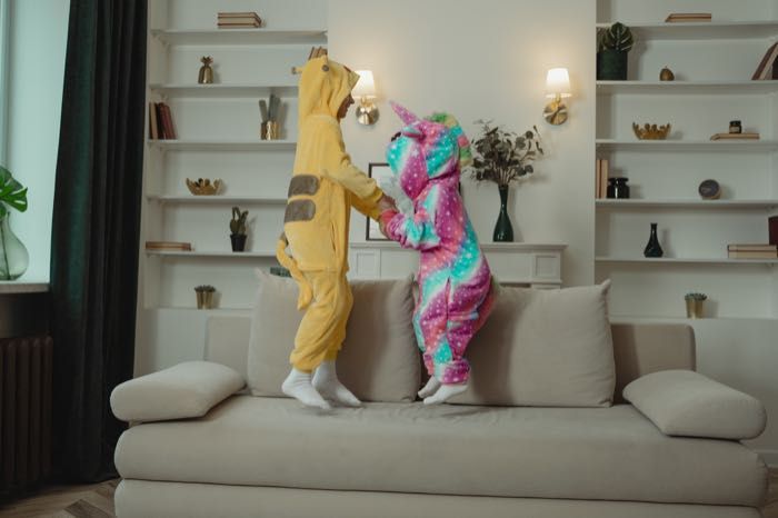 Two children in pajamas are jumping on a couch.