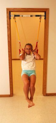 A young girl is sitting on a swing in a doorway.