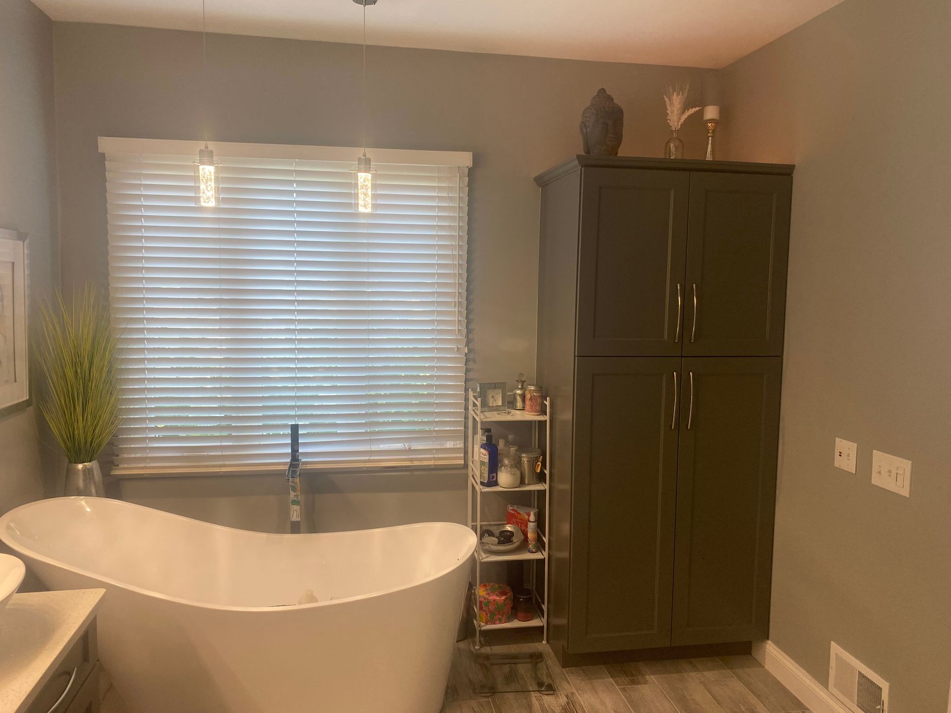 A bathroom with a tub , sink , cabinets and a window.