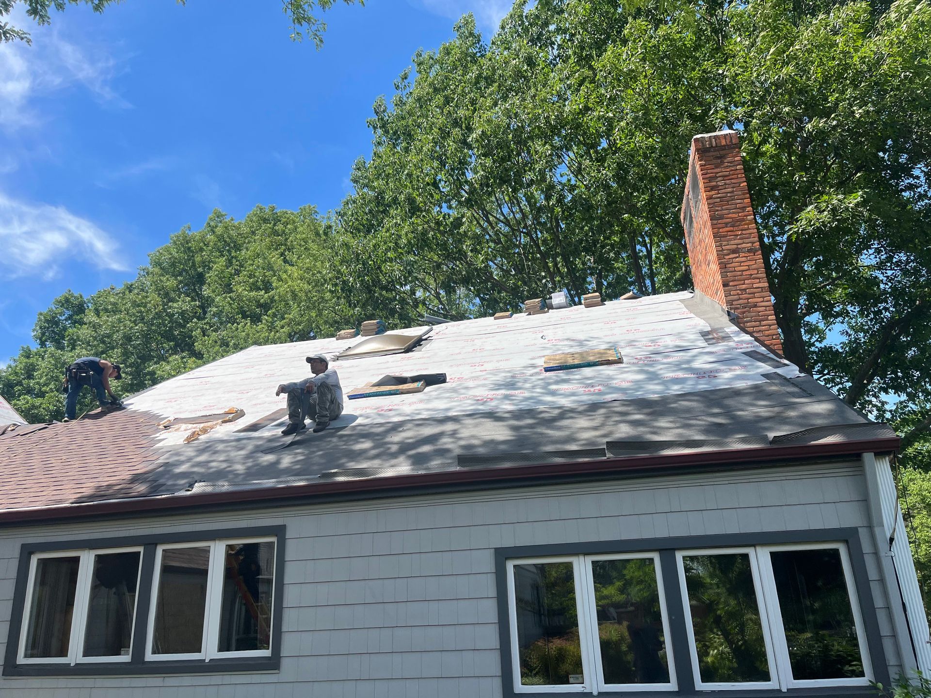 Two men are working on the roof of a house.