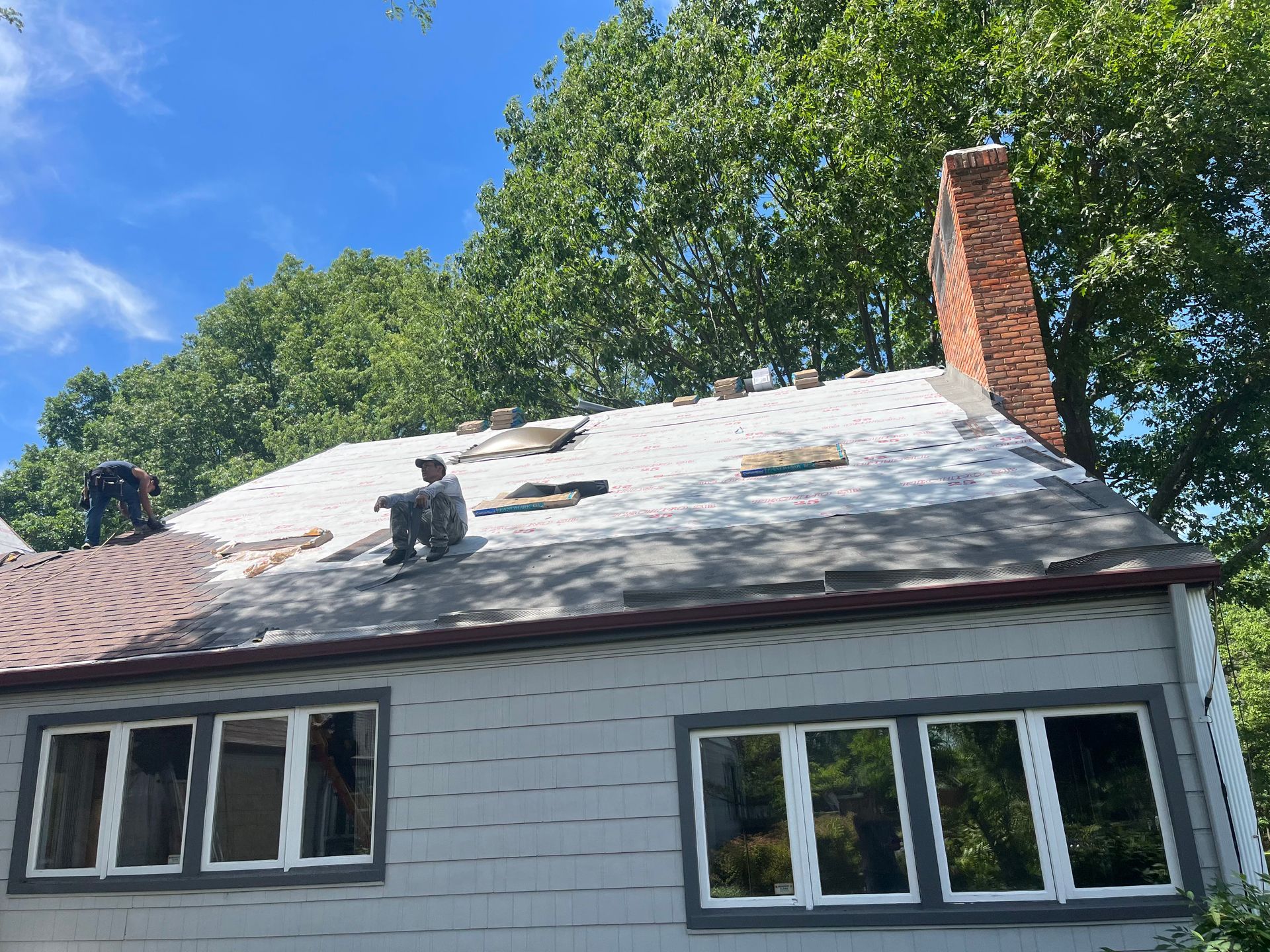 A man is sitting on the roof of a house.