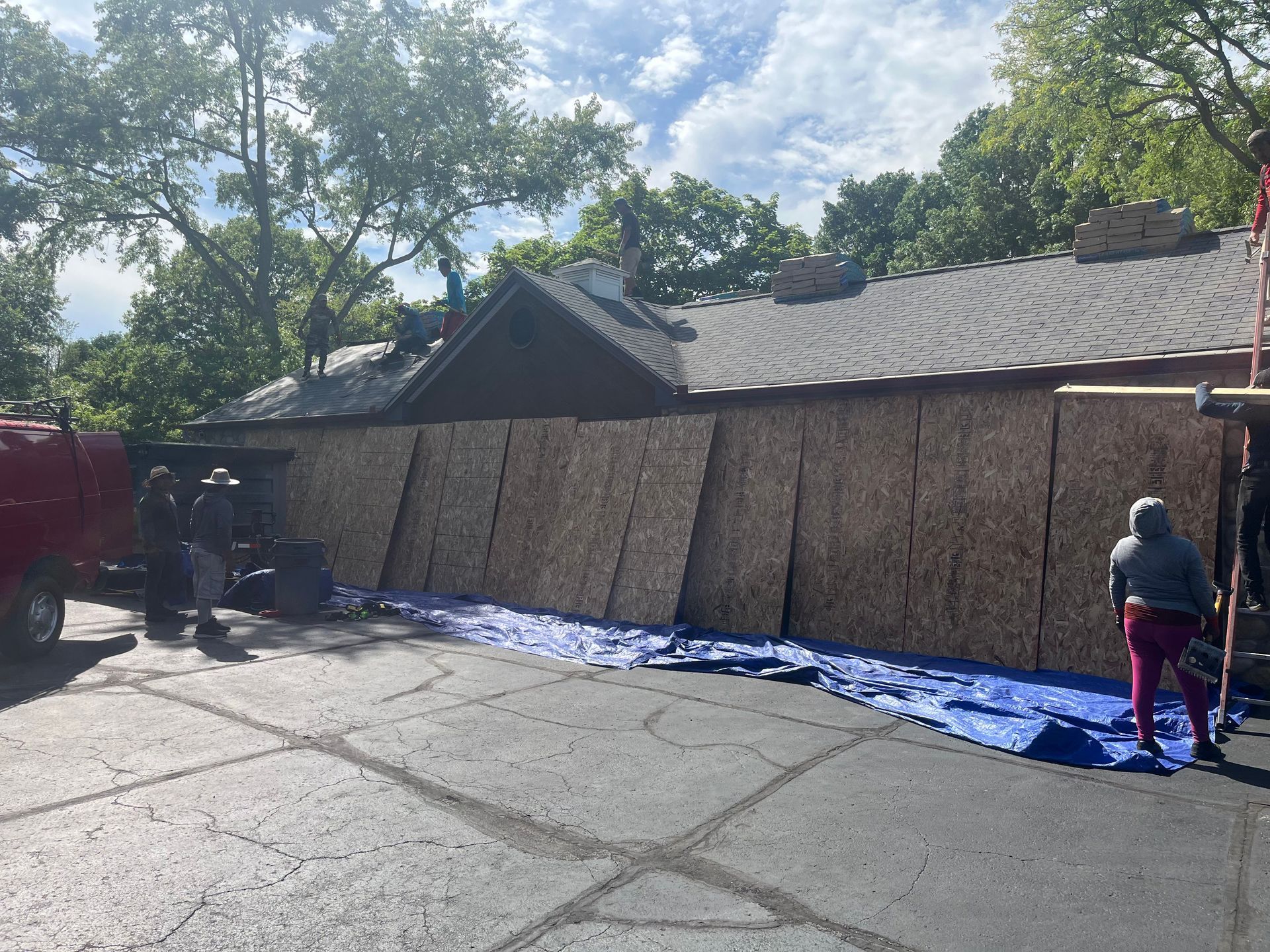 A group of people are working on a fence in front of a house.