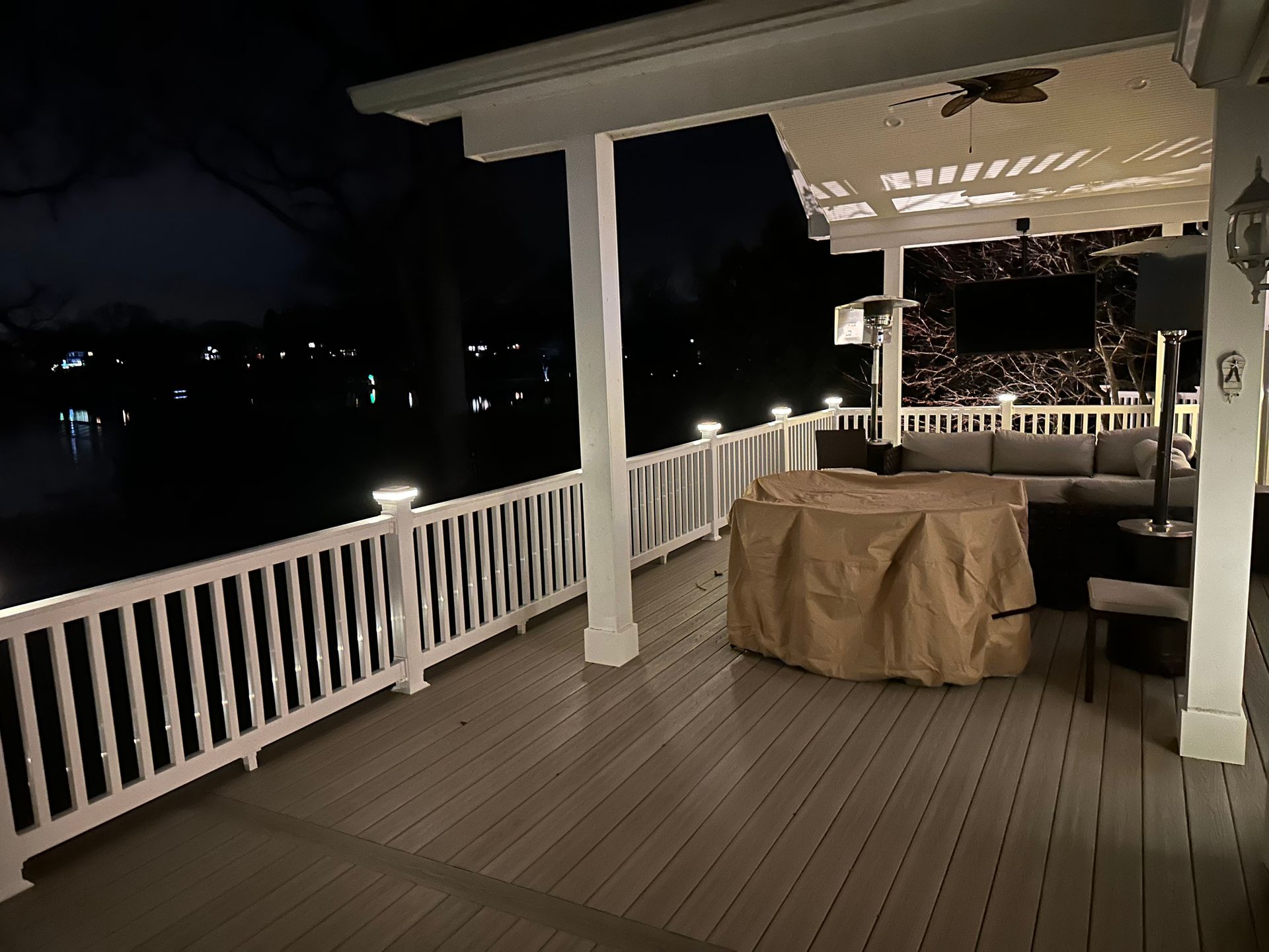 A deck with a fire pit and a couch on it at night.